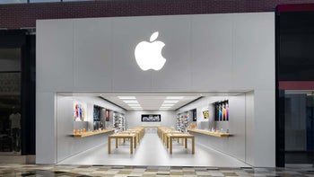 The front of an Apple Store insode a mall shows the entrance into the store along with the Apple logo above it.